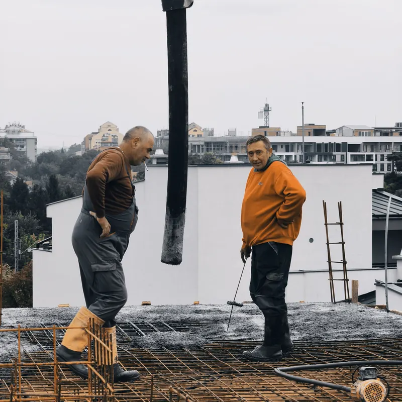 Tim majstora na sveže betoniranoj ploči sa pogledom na grad